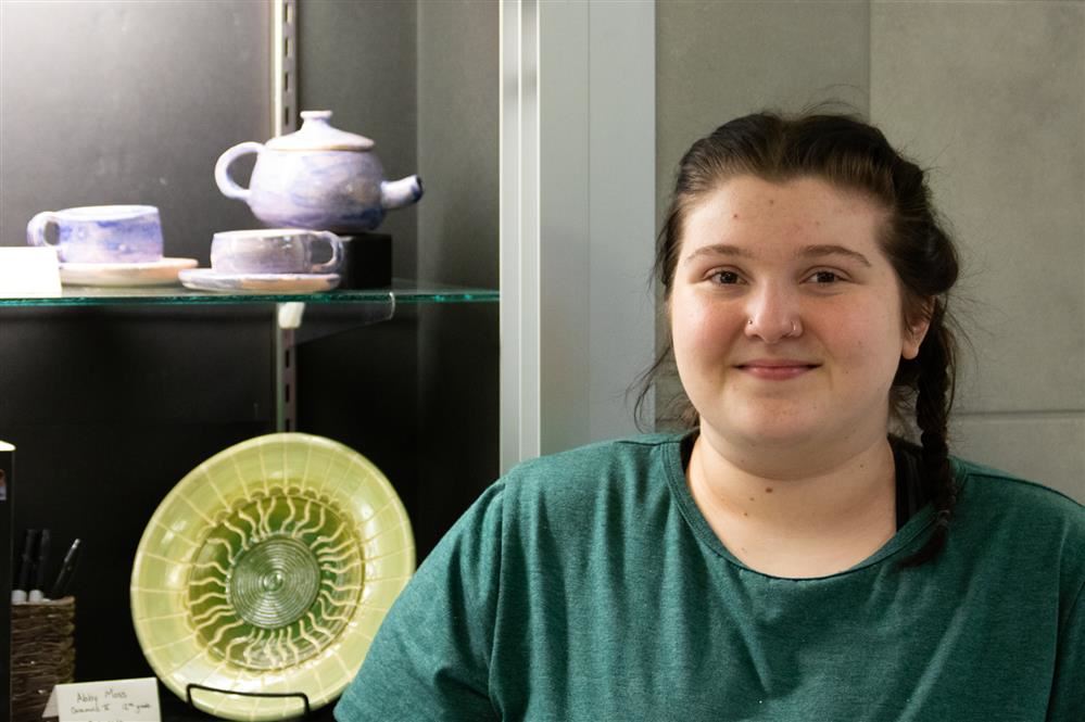  Student Jackie Wiggins Smiles beside her artwork